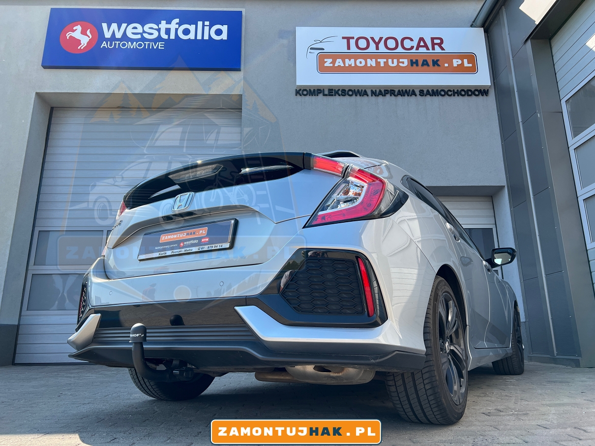 Zdjęcie przedstawia Hondę Civic z zamontowanym hakiem wypinanym ponowo Westfalia A40V, zrobione z tyłu, z prawej strony samochodu, na tle serwisu zamontujhak.pl 